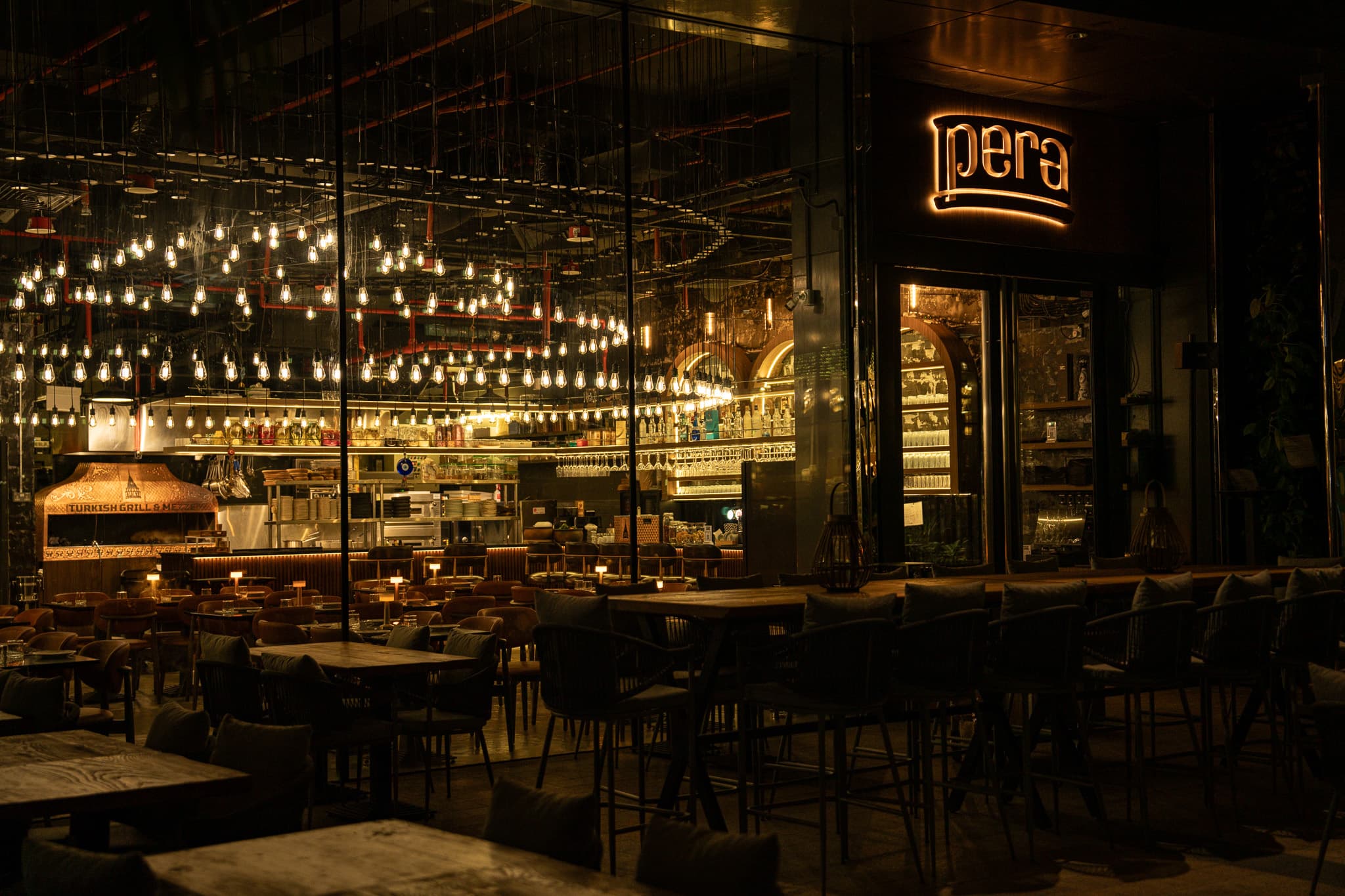 Pera's warmly lit main room with tables prepared for guests