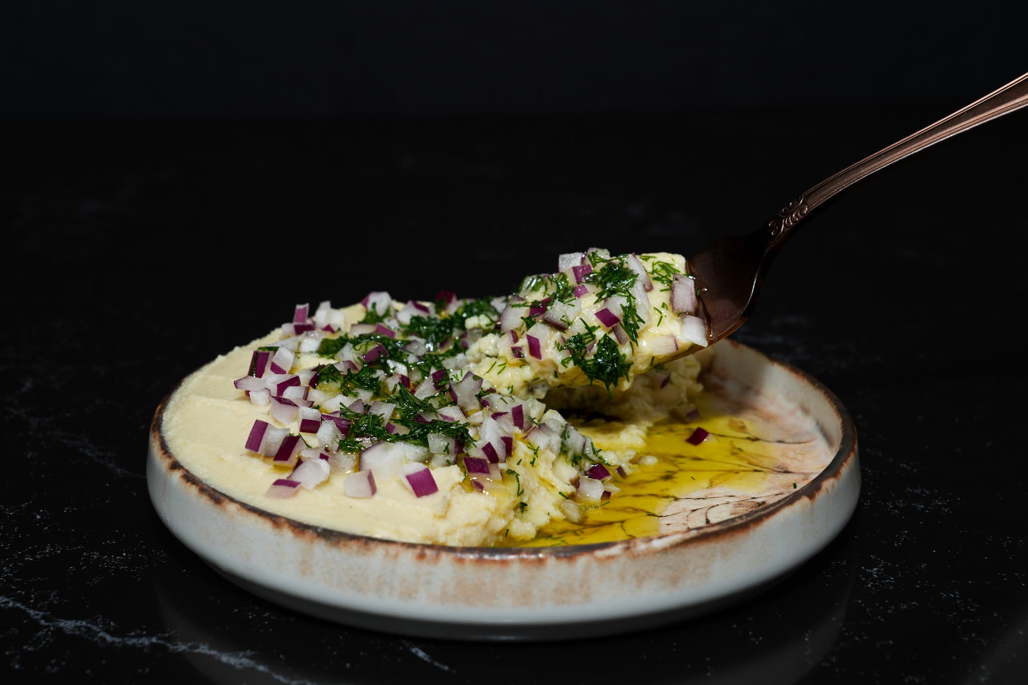 Creamy dip finished with herbs, onion, and olive oil