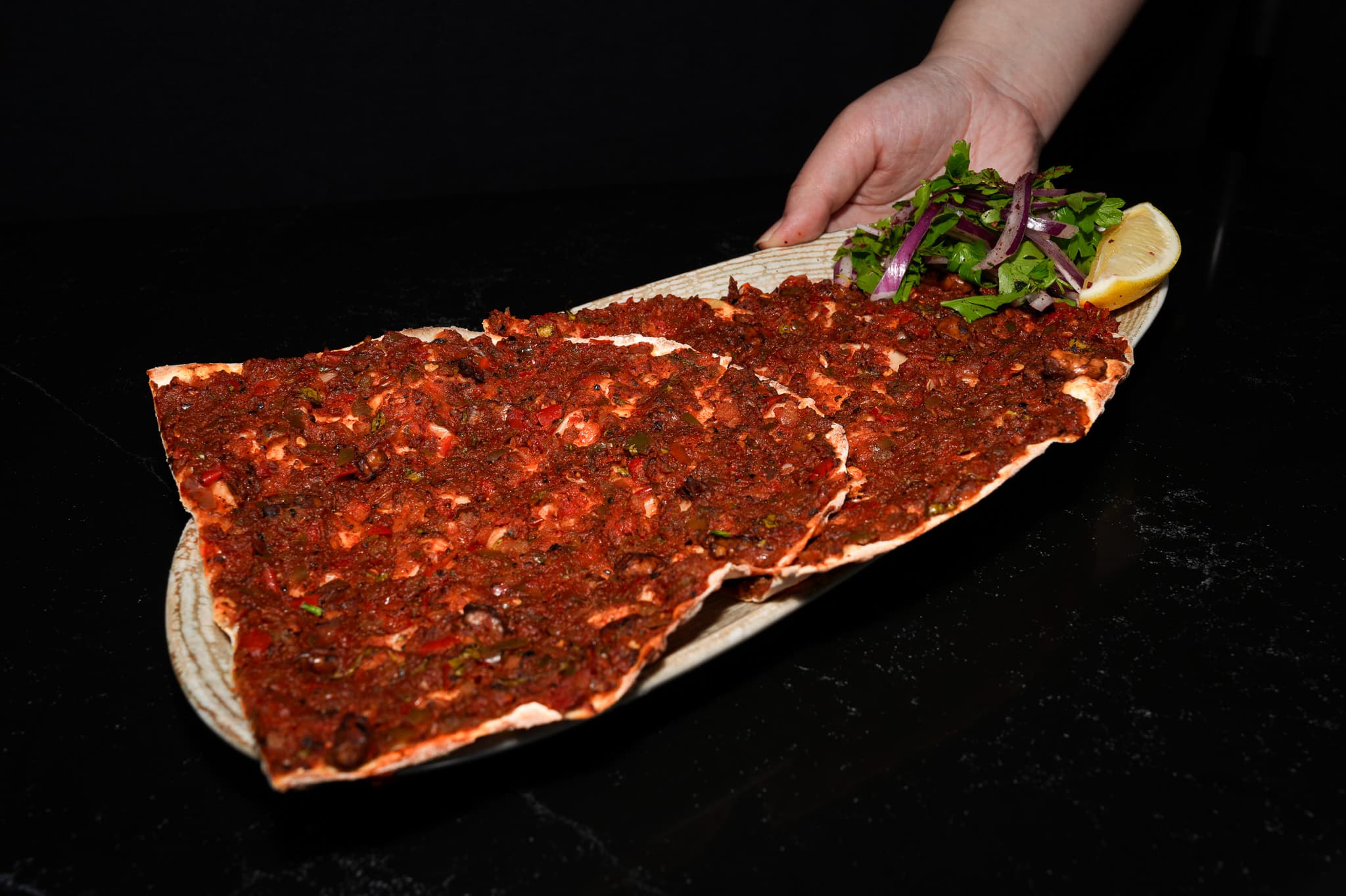Thin topped flatbread served with onion, herbs, and lemon